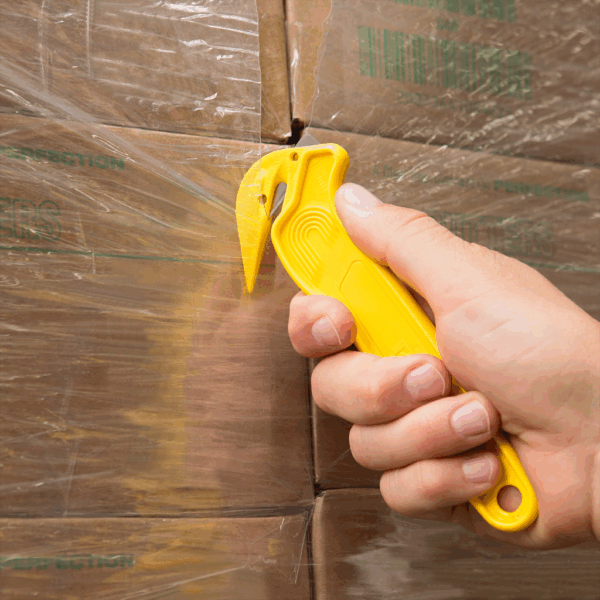 Notandi sker filmuplast (shrink wrap) utan um bretti með gulum öryggisskera